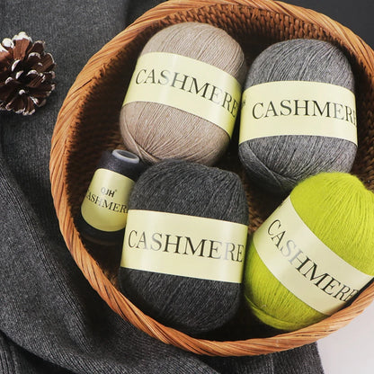 Basket with cashmere yarn balls labeled 'Cashmere' on a dark fabric background